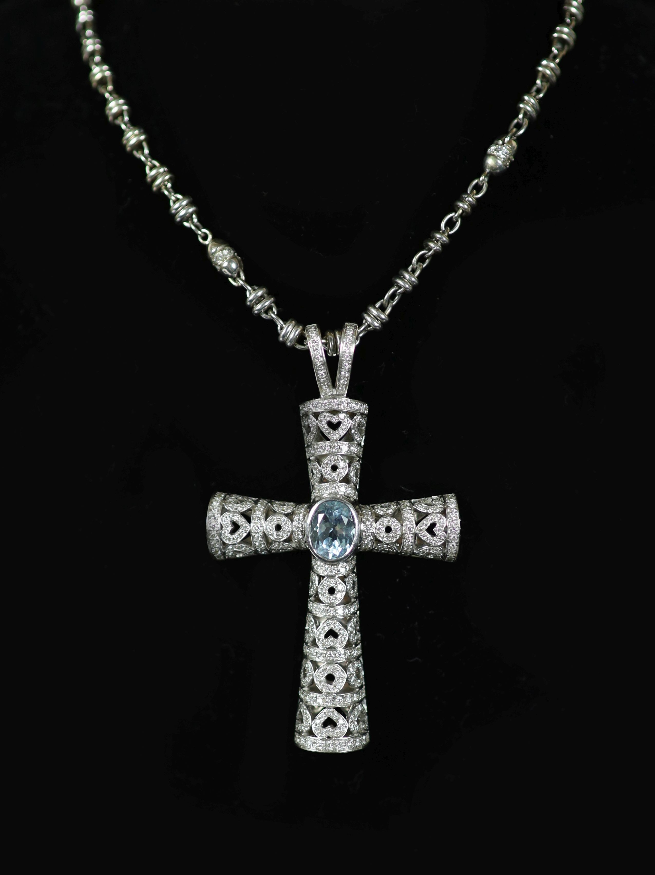 A Theo Fennell white gold, oval cut aquamarine and diamond chip cluster set pierced cross pendant, on a white gold and diamond set chain